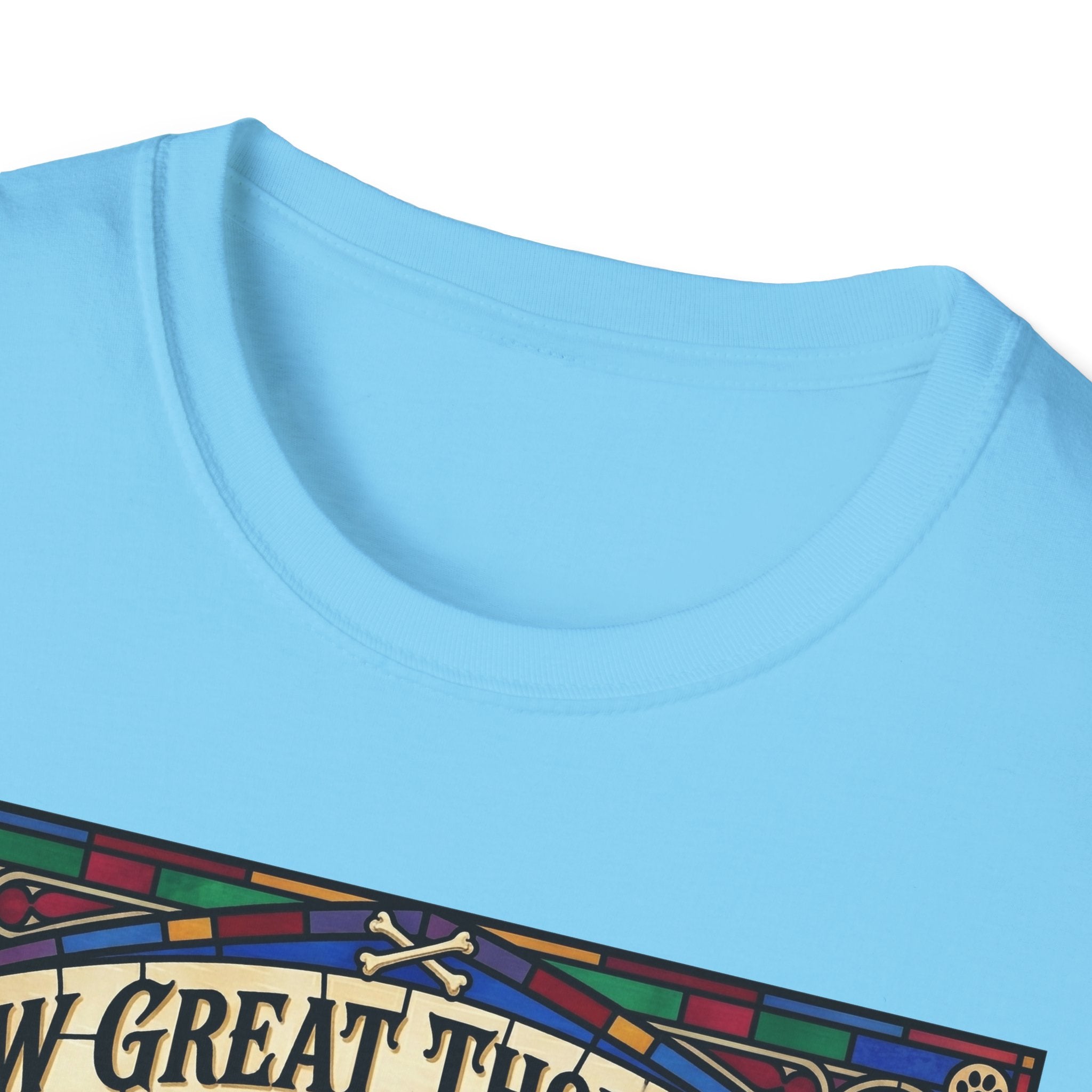 How Great Thou Bark Golden Retriever T-shirt close-up detail shot on a light blue shirt, showing the colorful stained-glass style graphic with crossbones and 'How Great Thou Bark' lettering at the neckline.