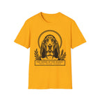 Holy Orders | Basset Hound T-Shirt flat lay on white shirt featuring a stained glass style illustration of a Basset Hound depicted as a holy figure with a golden halo and the text 'Holy Orders.'