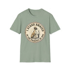 I Stand Amazed Great Dane T-Shirt flat lay in sage green, featuring a circular vintage-style graphic of a towering Great Dane with a halo and a small human figure, with text "I Stand Amazed in the Presence of Dog."