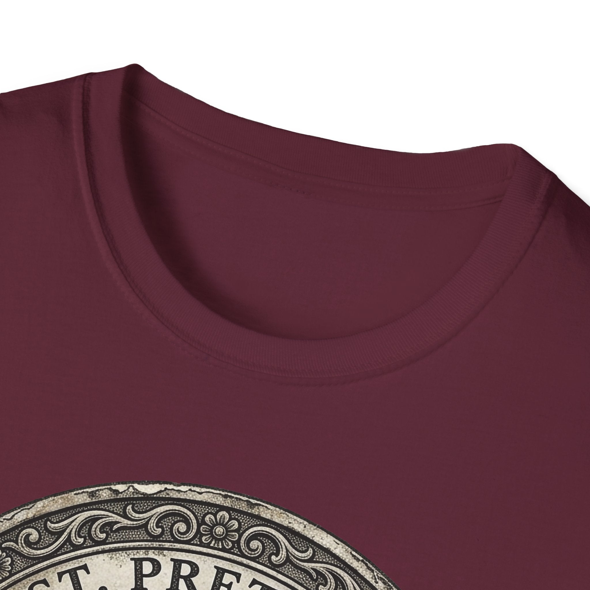 Saint Pretzel Forgive Us T-Shirt close-up detail shot on maroon shirt showing the neckline and top of the St. Pretzel engraved medallion graphic.