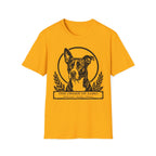 Holy Orders | Lobo T-Shirt flat lay on sage green shirt featuring a stained glass style illustration of Lobo, a black-coated dog with a white blaze and large upright ears, depicted as a holy figure with a golden halo and the text 'Holy Orders.'