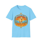 Believe in the Power of Dog Yellow Lab T-Shirt in light blue, flat lay view showing a retro-style oval badge with a halo-wearing yellow Labrador running joyfully through a sunlit field, with the words 'Joy Loyalty Love' and crossed bones.