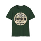Believe in the Power of Dog Paw T-shirt flat lay in forest green, featuring a circular vintage badge graphic of a dog paw raised like a fist from clouds above crossed bones, with paw print accents and bold text.