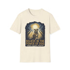 Believe in the Power Pitbull Clouds T-Shirt in natural cream, flat lay, featuring a dramatic illustrated graphic of a brindle Pitbull standing before a burst of heavenly light breaking through storm clouds, with text reading Believe in the Power of Dog and Strength, Resilience, Redemption.