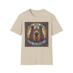 Holy Holy Holy St Bernard T-Shirt flat lay on sand, featuring a stained-glass-style illustration of a St Bernard seated before cathedral arches with the text 'Holy Holy Holy Lord Dog Almighty'.