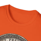 Saint Pretzel Forgive Us T-Shirt close-up detail shot on orange shirt showing the neckline and top of the St. Pretzel engraved medallion graphic.