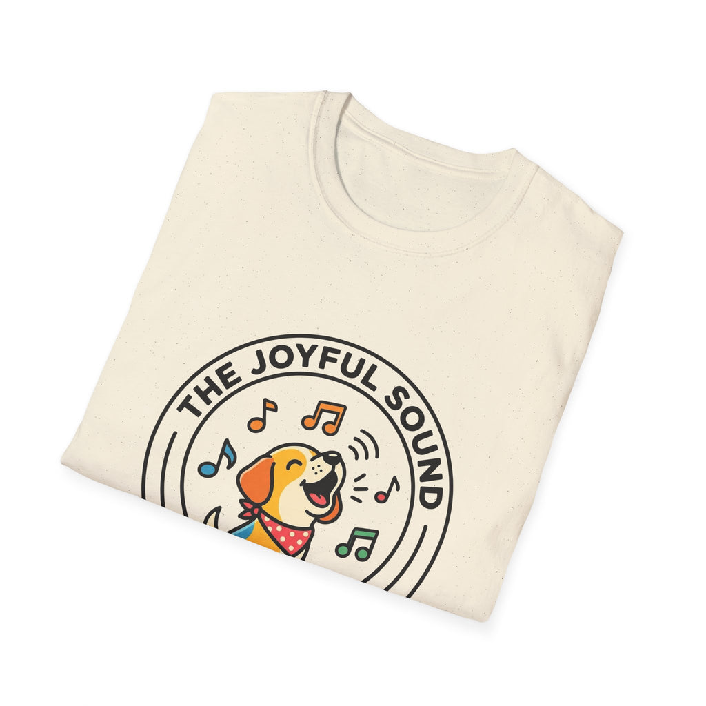 The Joyful Sound of Barking T-shirt folded view, natural tan shirt showing the circular badge graphic of a barking cartoon dog with musical notes and the text 'The Joyful Sound of Barking.'