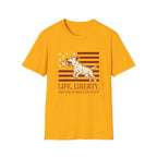 Pursuit of Fetch T-Shirt flat lay in gold yellow, featuring a leaping dog catching a tennis ball over a flag of red stripes and stars, with text reading 'Life, Liberty, and the Pursuit of Fetch.'
