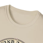 I Stand Amazed Chihuahua T-Shirt in sand, close-up of the neckline and upper graphic detail showing the circular Chihuahua design with crossed-bone medallion and vintage lettering.