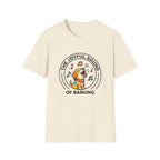 The Joyful Sound of Barking T-shirt flat lay, natural tan shirt featuring a circular badge graphic of a cartoon yellow dog with a red bandana howling joyfully with musical notes and the text 'The Joyful Sound of Barking.'