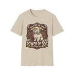 Believe in the Power of Dog Shih Tzu Throne T-Shirt in natural tan, flat lay, featuring a vintage badge graphic of a fluffy white Shih Tzu seated regally on a throne surrounded by lotus flowers and mountains, with text reading Believe in the Power of Dog and Grace, Wisdom, Devotion.
