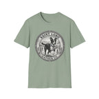 Saint Lobo Gather Us T-Shirt flat lay in sage green, featuring a vintage medallion graphic of a leaping border collie-style dog with a halo, surrounded by the text 'Saint Lobo — Gather Us.'