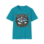Believe in the Power of Dog Bernese T-Shirt in teal, flat lay view showing a circular badge graphic with a halo-wearing Bernese Mountain Dog set against a mountain and forest landscape, with crossed bones and the words 'Loyalty Warmth Love'.