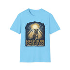 Believe in the Power Pitbull Clouds T-Shirt in light blue, flat lay, featuring a dramatic illustrated graphic of a brindle Pitbull standing before a burst of heavenly light breaking through storm clouds, with text reading Believe in the Power of Dog and Strength, Resilience, Redemption.