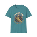 Praise Dog From Whom All Blessings Flow Labrador T-Shirt flat lay in teal blue, featuring a circular badge graphic of a golden Labrador gazing upward at a sunburst, surrounded by icons of a bone, tennis ball, paw print, and smiley face.