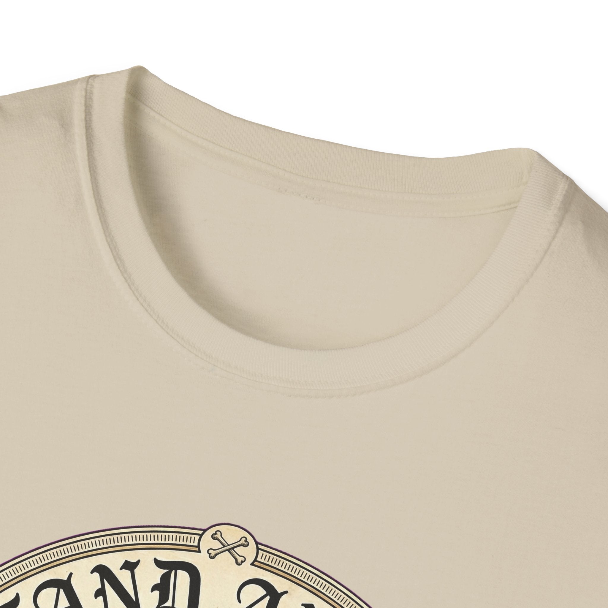 I Stand Amazed Golden Doodle T-Shirt close-up of the neckline and top of the graphic on a sand shirt, showing the ornate circular badge detail with crossed dog bones at the top.