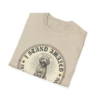 I Stand Amazed Golden Doodle T-Shirt folded view in sand, showing the golden doodle with halo graphic and "I Stand Amazed" lettering prominently on the front chest.