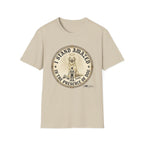 I Stand Amazed Golden Retriever T-Shirt flat lay in sand, featuring a circular vintage-style graphic of a golden retriever with a halo and the text "I Stand Amazed in the Presence of Dog" with Dogma House branding.