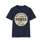 Believe in the Power of Dog Paw T-shirt flat lay in navy blue, featuring a circular vintage badge graphic of a dog paw raised like a fist from clouds above crossed bones, with paw print accents and bold text.