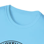 The Joyful Sound of Barking T-shirt close-up detail shot on a light blue shirt, showing the circular badge graphic with the 'Joyful Sound' lettering at the neckline.