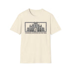 A Mighty Fortress is Our Dog T-Shirt flat lay in natural/cream featuring a detailed gothic cathedral illustration with a dog standing in the doorway, framed in an ornate border with text below.