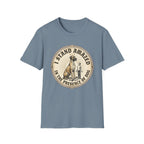 I Stand Amazed Great Dane T-Shirt flat lay in slate blue, featuring a circular vintage-style graphic of a towering Great Dane with a halo standing beside a tiny human figure, with text "I Stand Amazed in the Presence of Dog" around the badge.