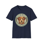 Dog is Love T-Shirt flat lay in navy blue featuring a vintage circular badge graphic with a scruffy terrier face, "Dog is Love" arched above and "Unconditional Forever" below.
