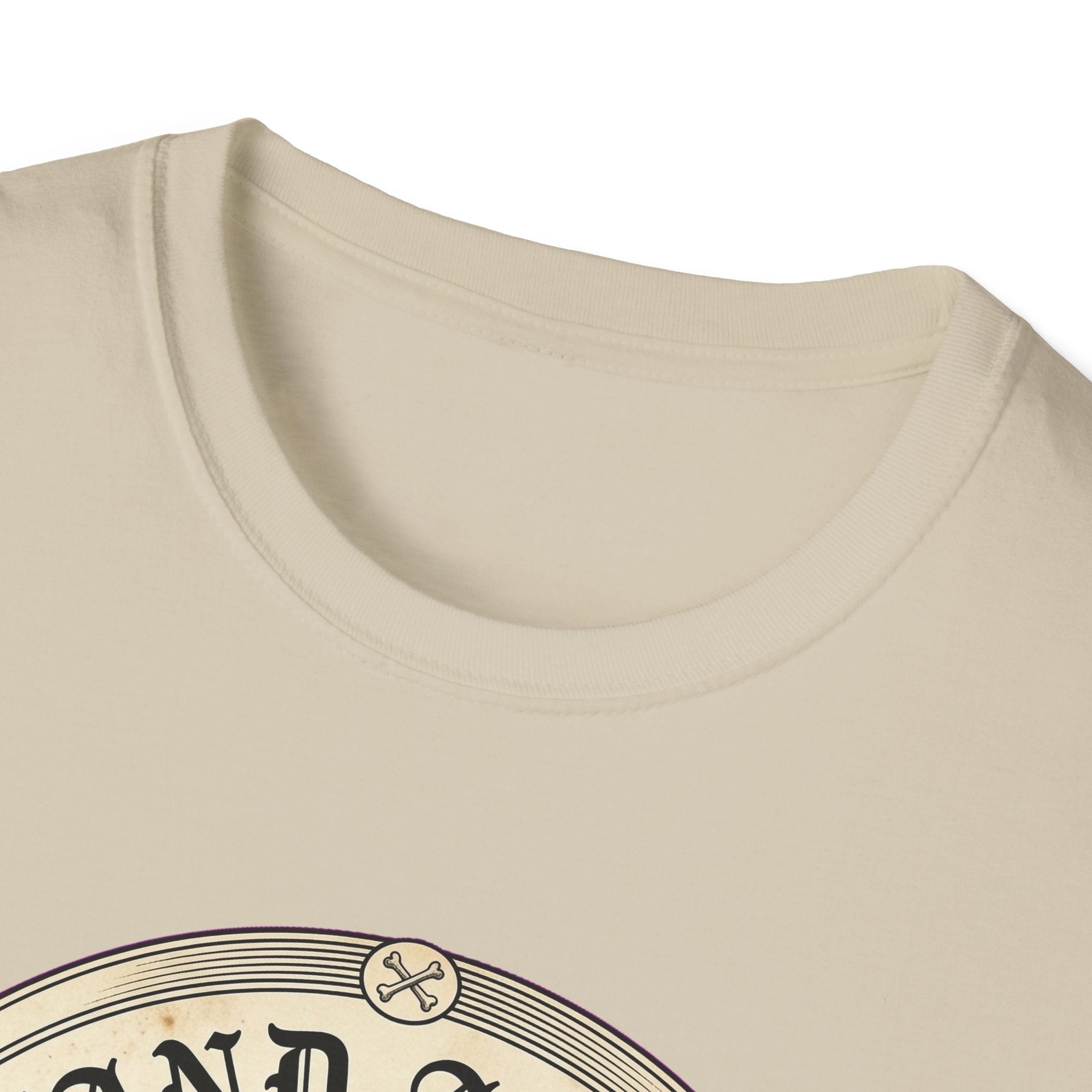 I Stand Amazed Rescue Mutt T-Shirt in sand, close-up of the neckline and upper graphic detail showing the circular rescue mutt design with crossed-bone medallion and vintage lettering.