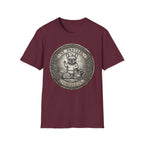 Saint Pretzel Forgive Us T-Shirt flat lay on maroon shirt featuring an engraved medallion design with a French Bulldog saint, a squirrel, and a raccoon, reading St. Pretzel Forgive Us.