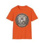 Saint Pretzel Forgive Us T-Shirt flat lay on orange shirt featuring an engraved medallion design with a French Bulldog saint and the text St. Pretzel Forgive Us.
