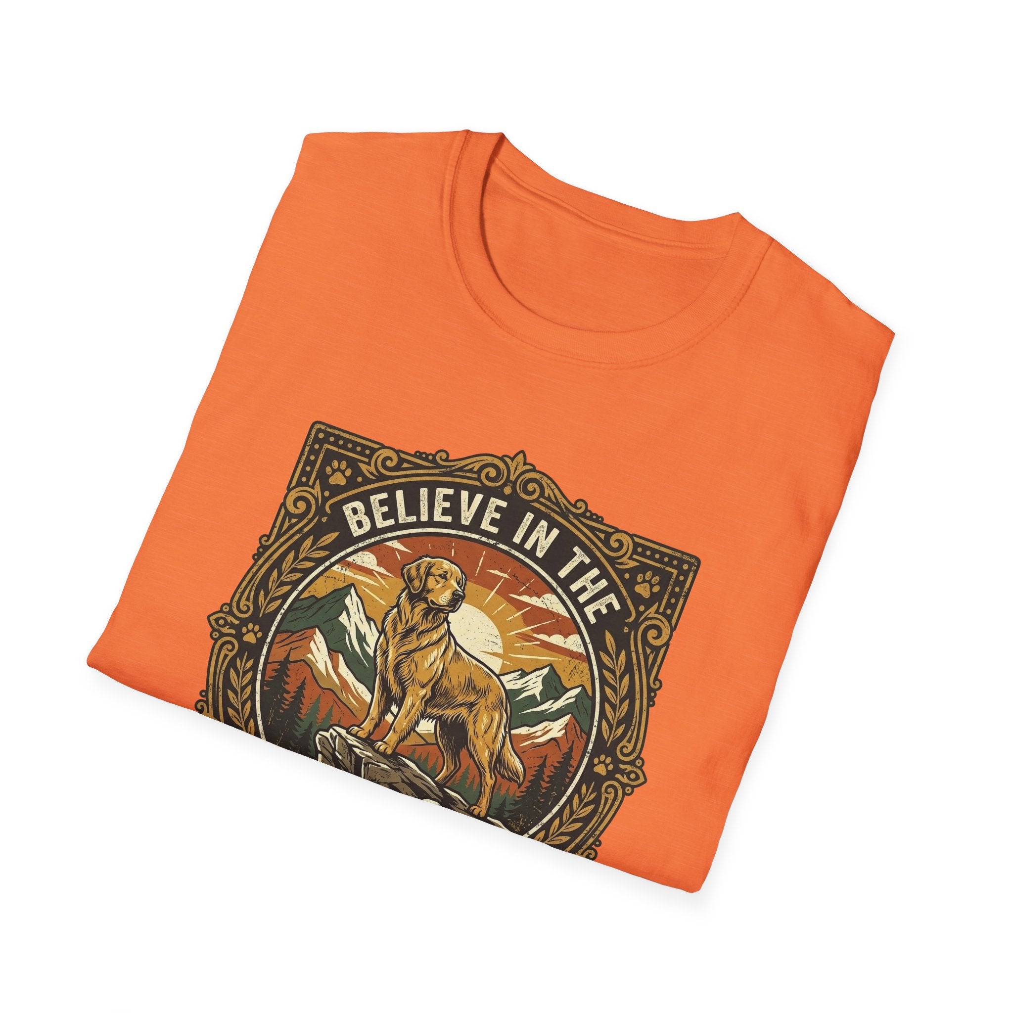 Believe in the Power of Dog T-shirt folded flat lay in orange, showing the ornate vintage badge graphic of a Labrador on a rocky mountain outcrop with 'Believe in the' arched text at top.