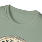 I Stand Amazed Rescue Mutt T-Shirt in sage green, close-up of the neckline and upper graphic detail showing the circular rescue mutt design with crossed-bone medallion and vintage lettering.