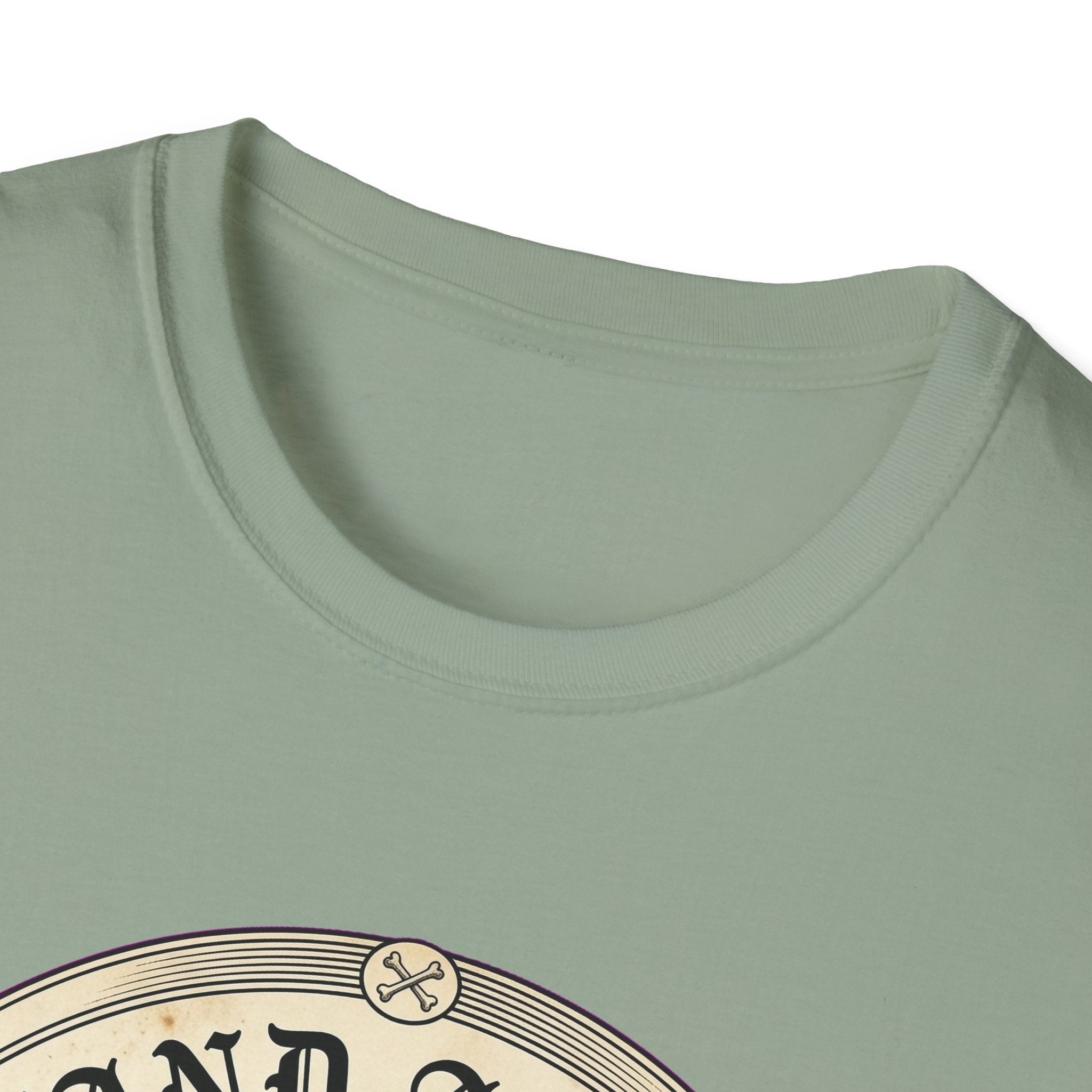 I Stand Amazed Rescue Mutt T-Shirt in sage green, close-up of the neckline and upper graphic detail showing the circular rescue mutt design with crossed-bone medallion and vintage lettering.