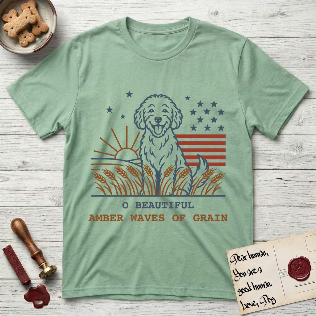 Amber Waves of Grain T-Shirt flat lay in Mint Green, featuring a faded vintage-Americana line-art Goldendoodle sitting in a wheat field with a rising sun, scattered stars, and red flag stripes, above “O Beautiful / Amber Waves of Grain” lettering.