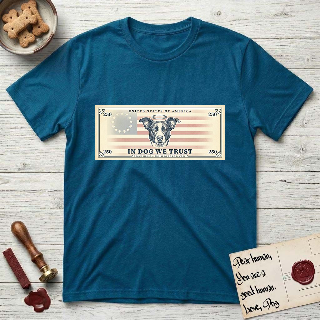 In Dog We Trust Bill T-Shirt flat lay in Antique Sapphire, featuring a vintage dollar-bill design with a haloed mixed-breed Dog at center, a Betsy Ross flag in the background, and bold currency-style "In Dog We Trust" typography.