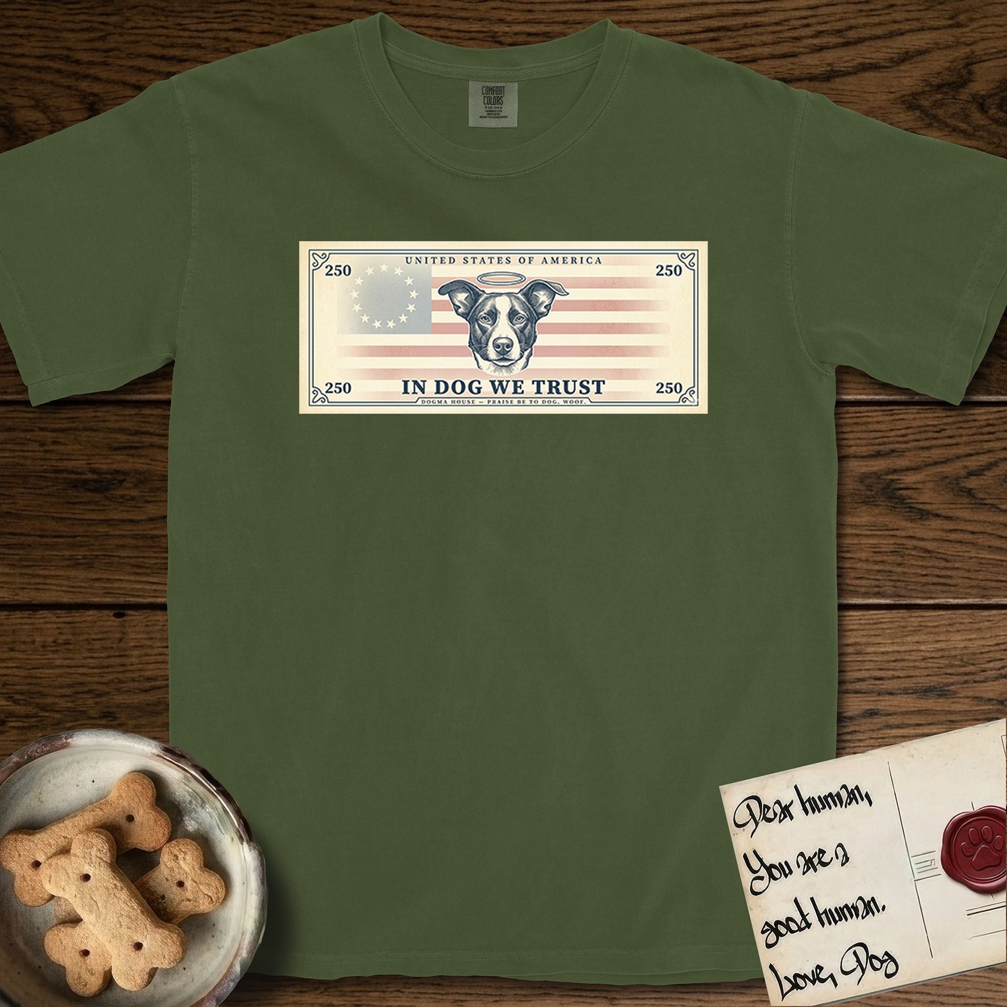 In Dog We Trust Bill T-Shirt flat lay in Hemp, featuring a vintage dollar-bill design with a haloed mixed-breed Dog at center, a Betsy Ross flag in the background, and bold currency-style "In Dog We Trust" typography.