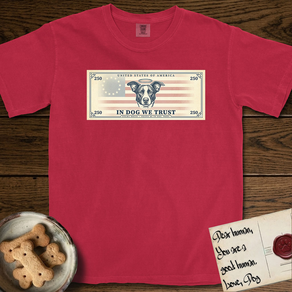 In Dog We Trust Bill T-Shirt flat lay in Red, featuring a vintage dollar-bill design with a haloed mixed-breed Dog at center, a Betsy Ross flag in the background, and bold currency-style "In Dog We Trust" typography.