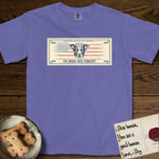 In Dog We Trust Bill T-Shirt flat lay in Violet, featuring a vintage dollar-bill design with a haloed mixed-breed Dog at center, a Betsy Ross flag in the background, and bold currency-style "In Dog We Trust" typography.