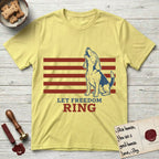 Let Freedom Ring T-Shirt flat lay in Cornsilk, featuring a faded vintage-Americana line-art Beagle sitting and baying with her head thrown back in front of red flag stripes, above “Let Freedom Ring” lettering.