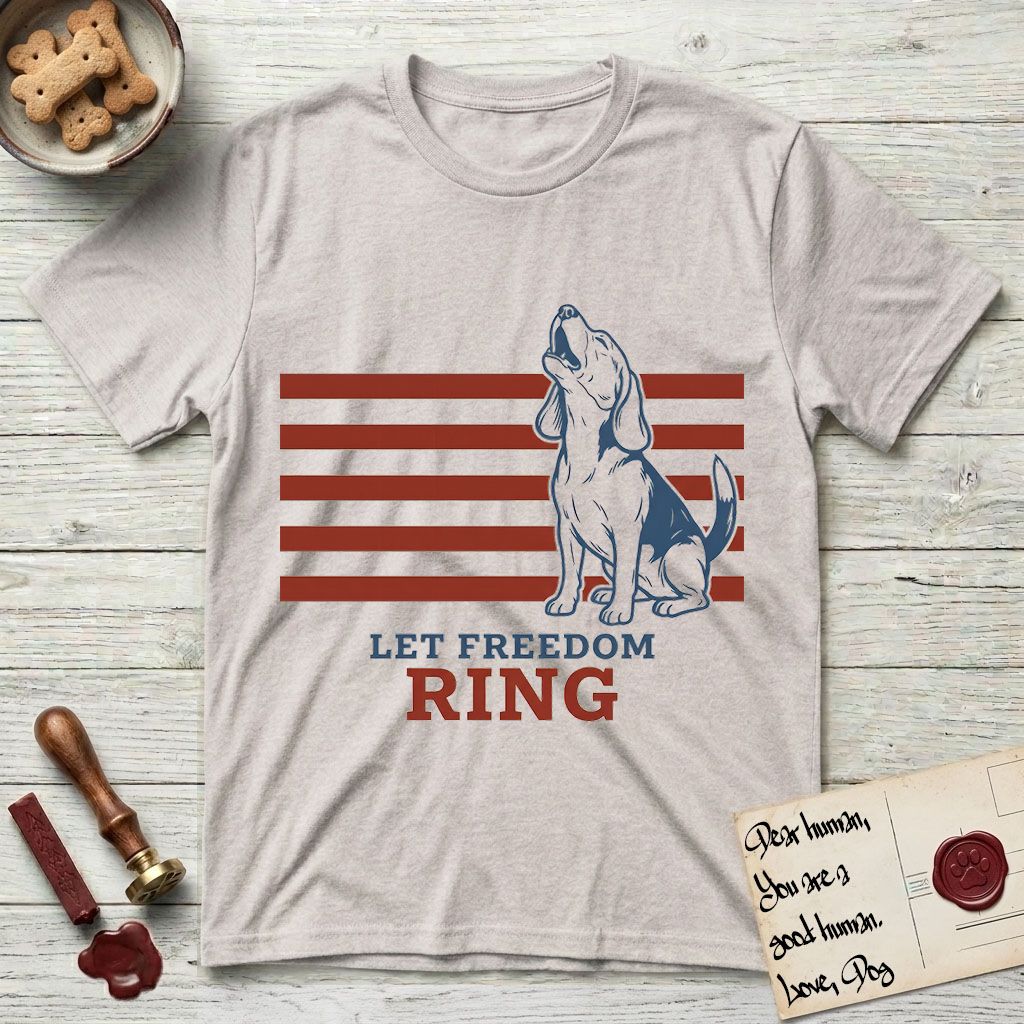 Let Freedom Ring T-Shirt flat lay in Ice Grey, featuring a faded vintage-Americana line-art Beagle sitting and baying with her head thrown back in front of red flag stripes, above “Let Freedom Ring” lettering.