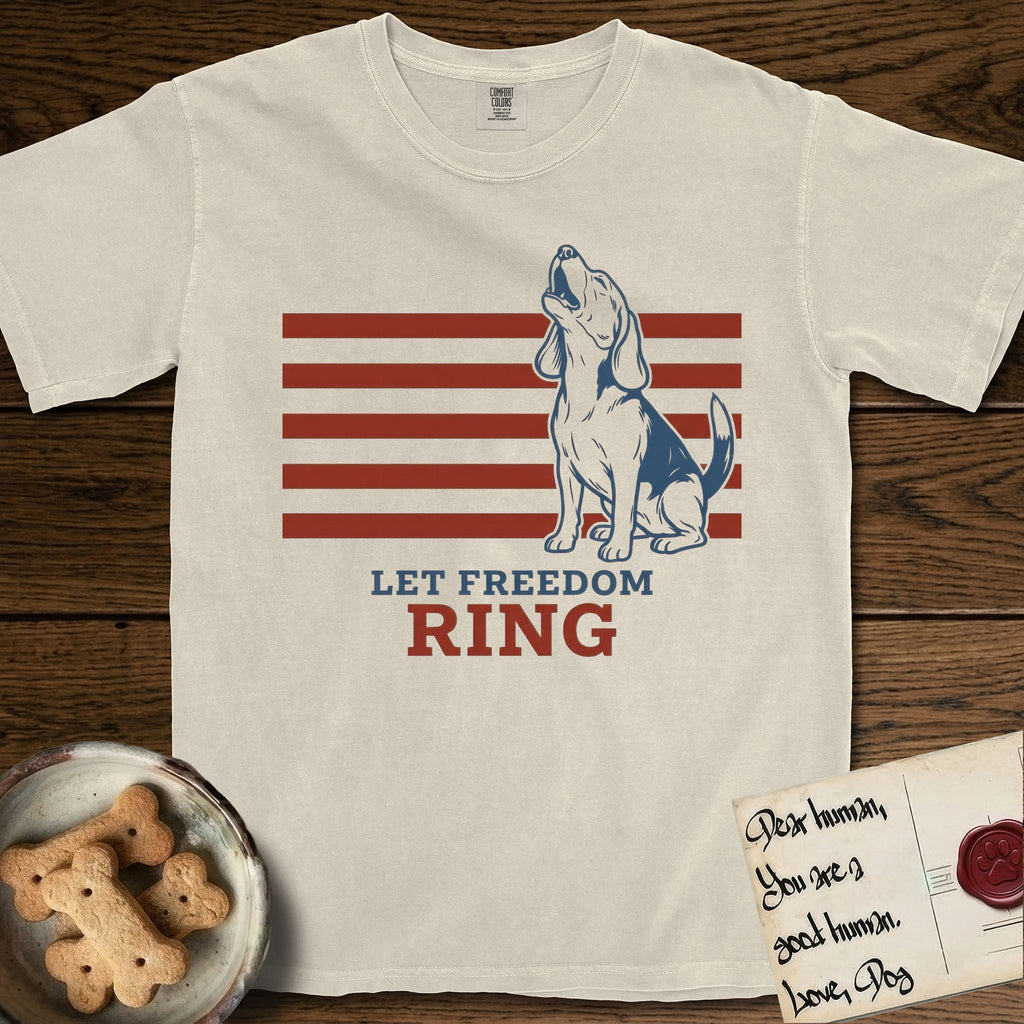 Let Freedom Ring T-Shirt flat lay in Ivory, featuring a faded vintage-Americana line-art Beagle sitting and baying with her head thrown back in front of red flag stripes, above “Let Freedom Ring” lettering.