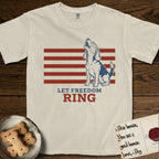 Let Freedom Ring T-Shirt flat lay in Ivory, featuring a faded vintage-Americana line-art Beagle sitting and baying with her head thrown back in front of red flag stripes, above “Let Freedom Ring” lettering.