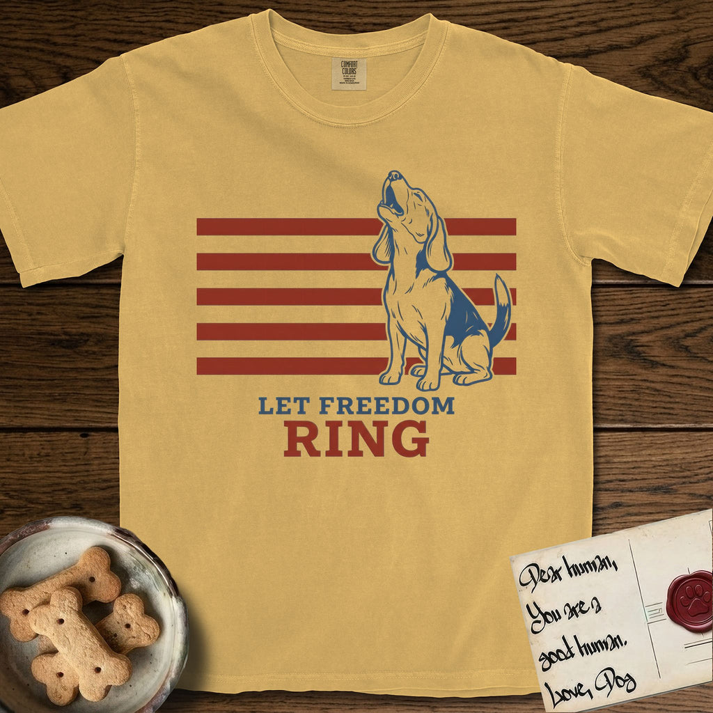 Let Freedom Ring T-Shirt flat lay in Mustard, featuring a faded vintage-Americana line-art Beagle sitting and baying with her head thrown back in front of red flag stripes, above “Let Freedom Ring” lettering.