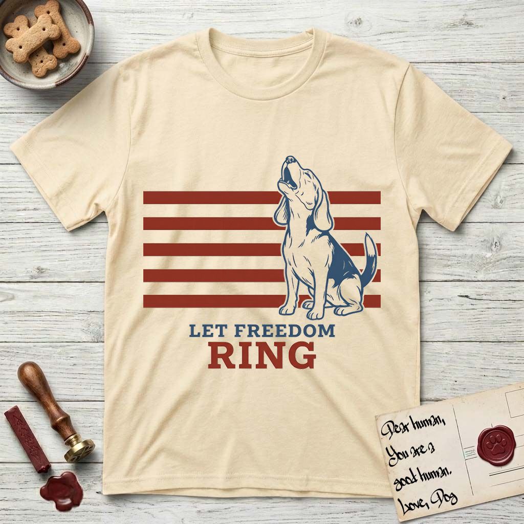 Let Freedom Ring T-Shirt flat lay in Natural, featuring a faded vintage-Americana line-art Beagle sitting and baying with her head thrown back in front of red flag stripes, above “Let Freedom Ring” lettering.