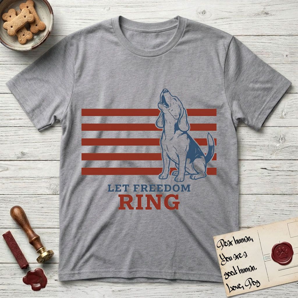 Let Freedom Ring T-Shirt flat lay in Sport Grey, featuring a faded vintage-Americana line-art Beagle sitting and baying with her head thrown back in front of red flag stripes, above “Let Freedom Ring” lettering.