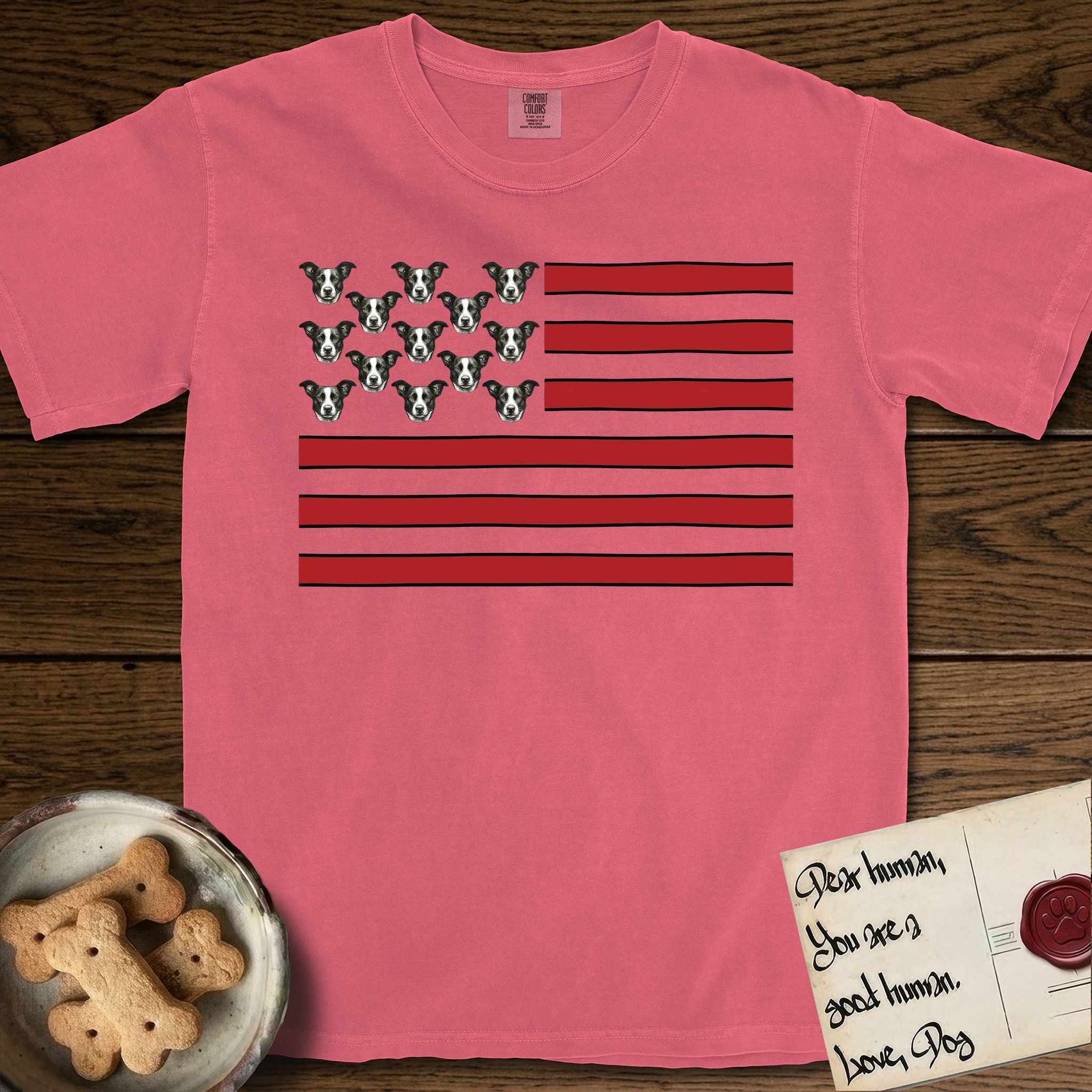 Lobo Head Flag T-Shirt flat lay in Watermelon, featuring an American flag with thirteen repeated black-and-white photos of a Pitbull-and-cattle-dog-mix Dog head in place of the stars and dusty red stripes.