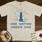 One Nation Under Dog T-Shirt flat lay in Ivory, featuring a minimalist design with a Dog silhouette over a radiating sunburst, five stars, and bold "One Nation Under Dog" typography.