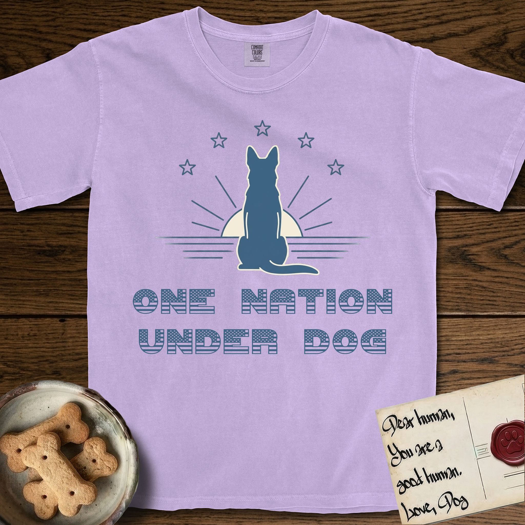 One Nation Under Dog T-Shirt flat lay in Orchid, featuring a minimalist design with a Dog silhouette over a radiating sunburst, five stars, and bold "One Nation Under Dog" typography.