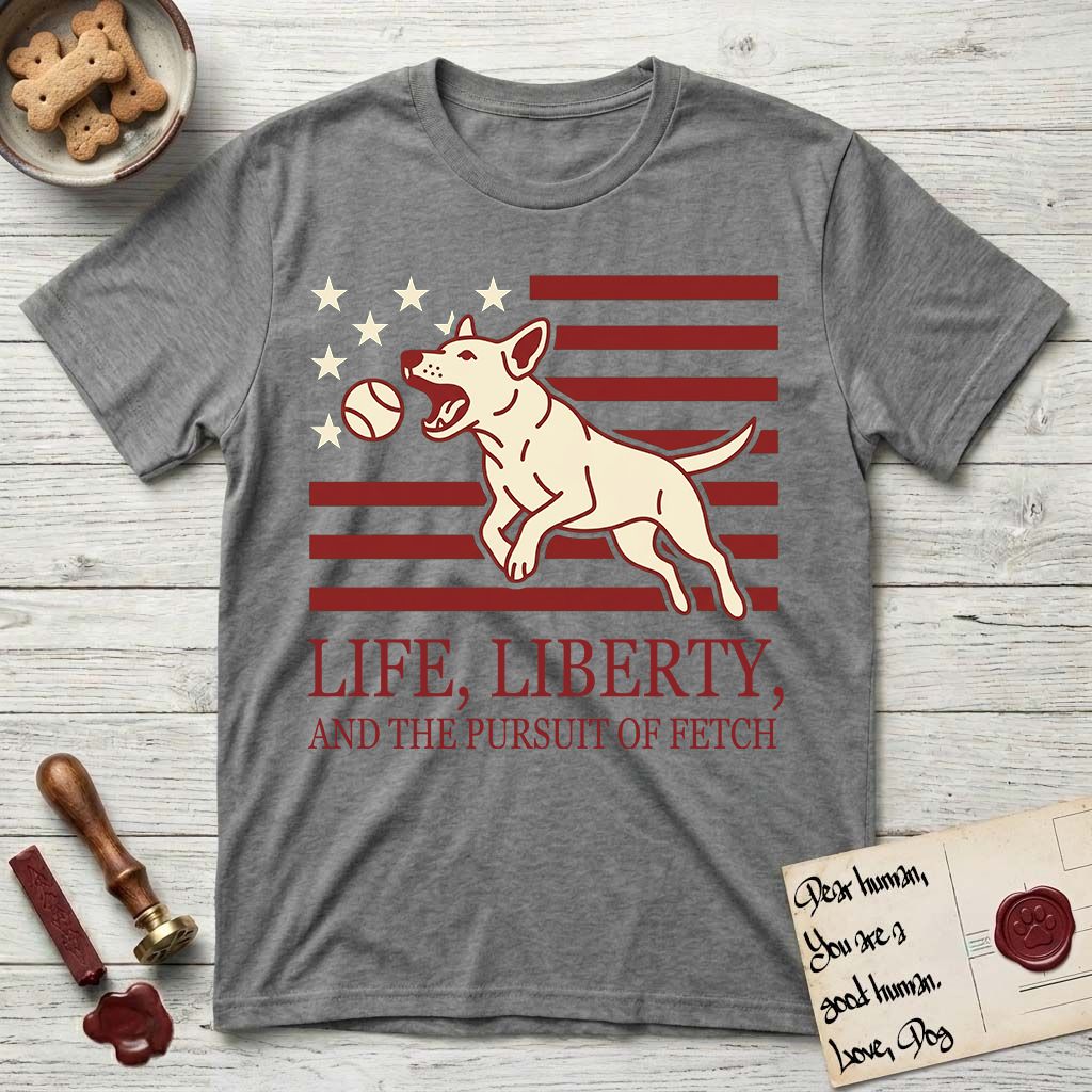 Life, Liberty, and the Pursuit of Fetch T-Shirt flat lay in Graphite Heather, featuring a square flag-inspired design with a Bull Terrier leaping after a ball, cream stars, and bold "Life, Liberty, and the Pursuit of Fetch" serif typography.