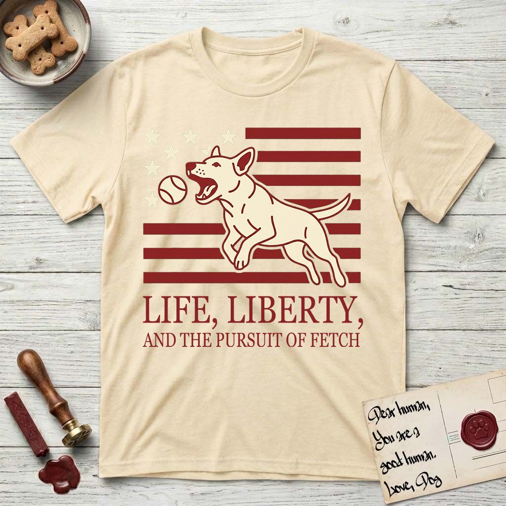 Life, Liberty, and the Pursuit of Fetch T-Shirt flat lay in Natural, featuring a square flag-inspired design with a Bull Terrier leaping after a ball, cream stars, and bold "Life, Liberty, and the Pursuit of Fetch" serif typography.